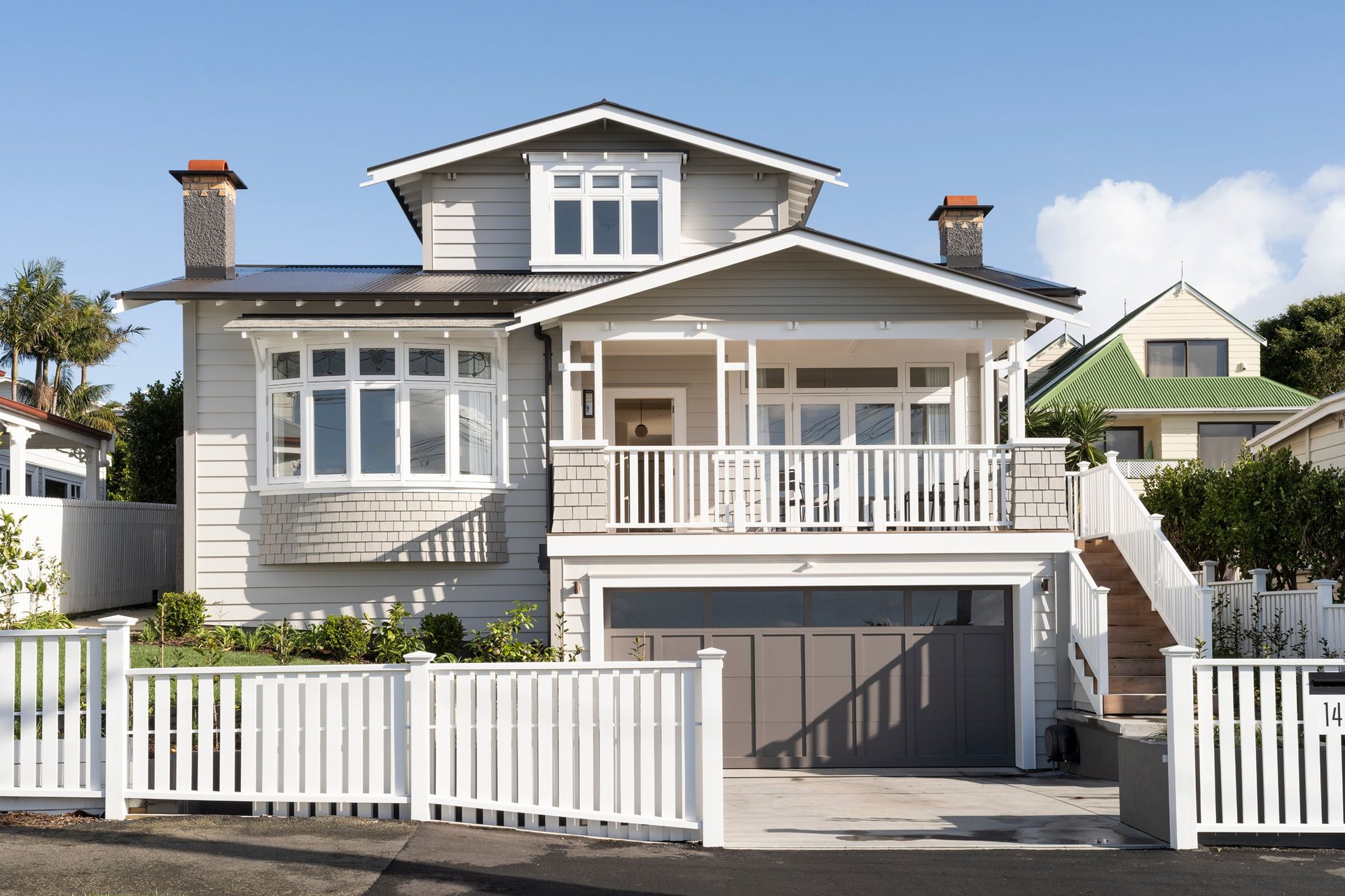 A weatherboard New Zealand house behind a white picket fence.